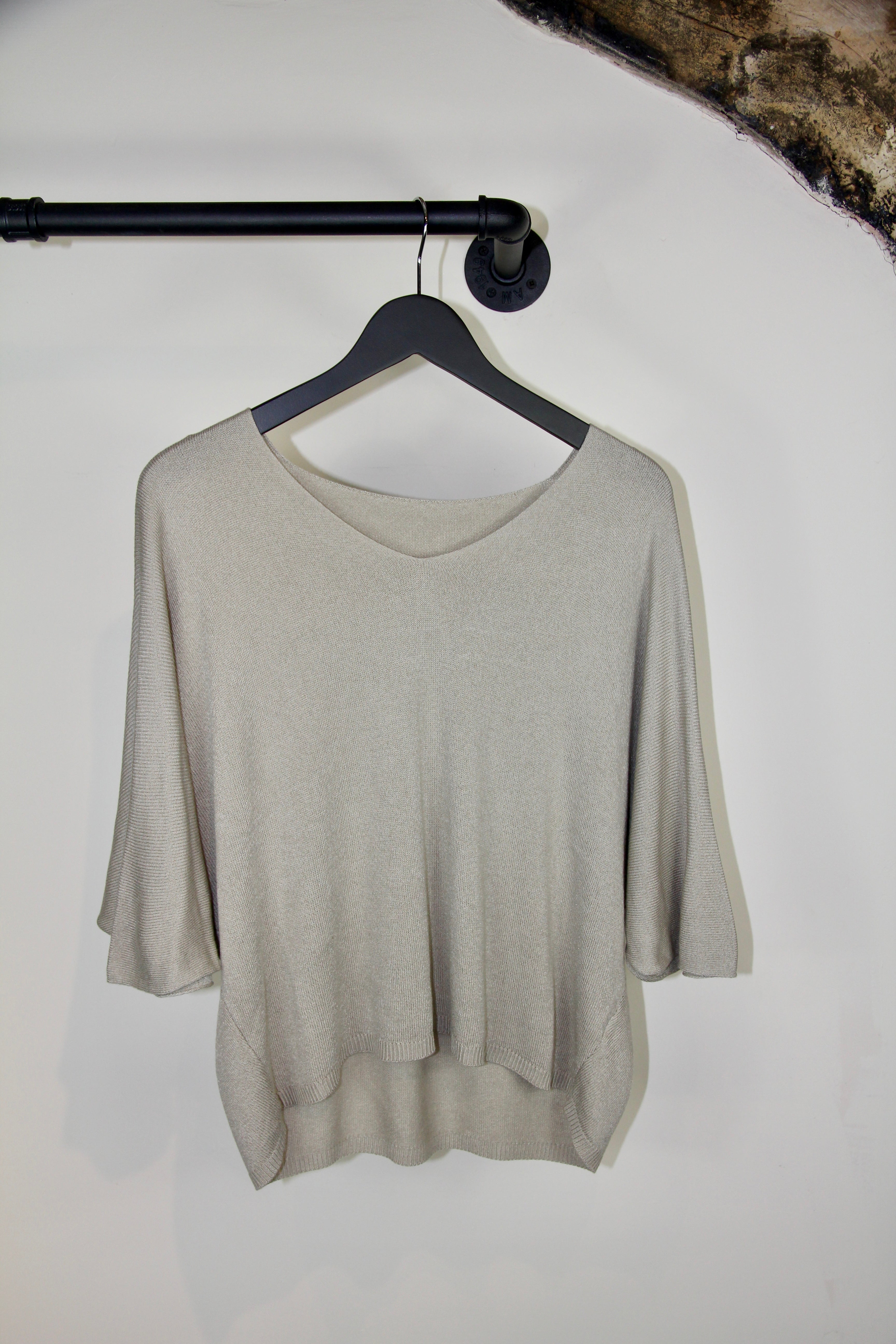 Beige sweater on a hanger against a white wall